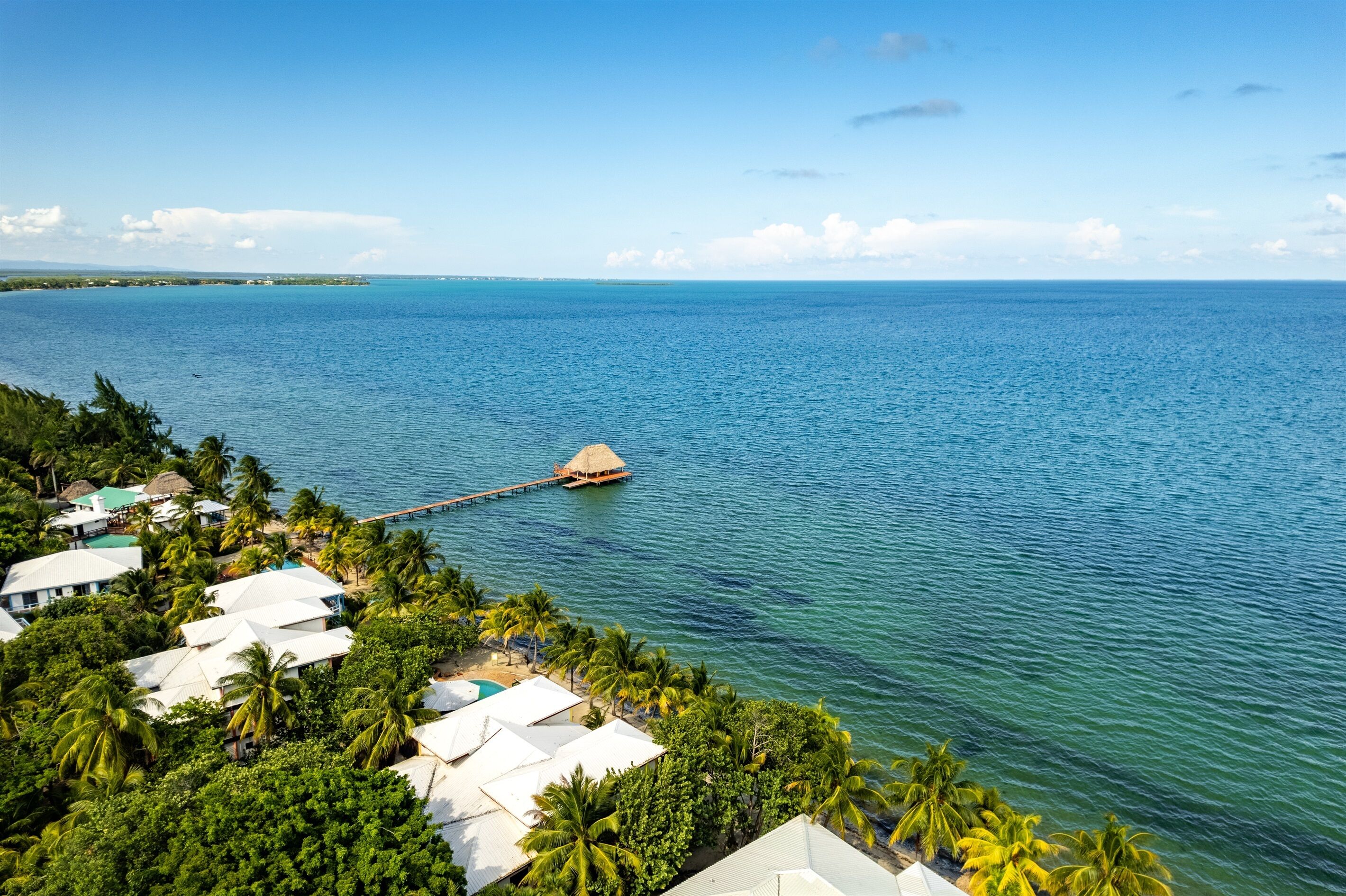 Ein tropisches Resort mit überwasser Bungalows, die durch eine Holzstege verbunden sind.