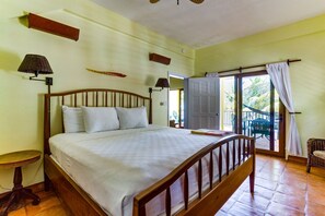 Une chambre à coucher avec un lit en bois, une petite table, une lampe et une vue sur l’extérieur.