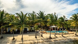 Ein Strandresort mit Schwimmbad, Palmen und einem Pavillon.