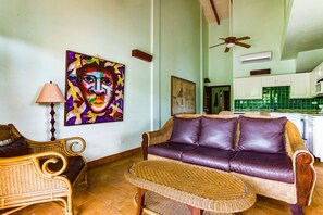 Un salon avec un canapé, une table en osier et un tableau accroché au mur.