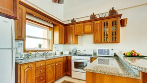 Una cocina con armarios de madera, encimeras de granito, estufa y microondas.