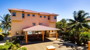 Un hotel de varios pisos con techo rojo, un espacio al aire libre cubierto y palmeras.