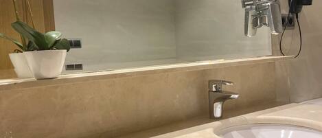 Un baño con dos lavamanos, un espejo, un secador de pelo y una orquídea en maceta.
