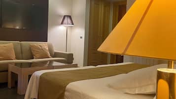 Una habitación de hotel con cama, sofá, lámpara y televisor.