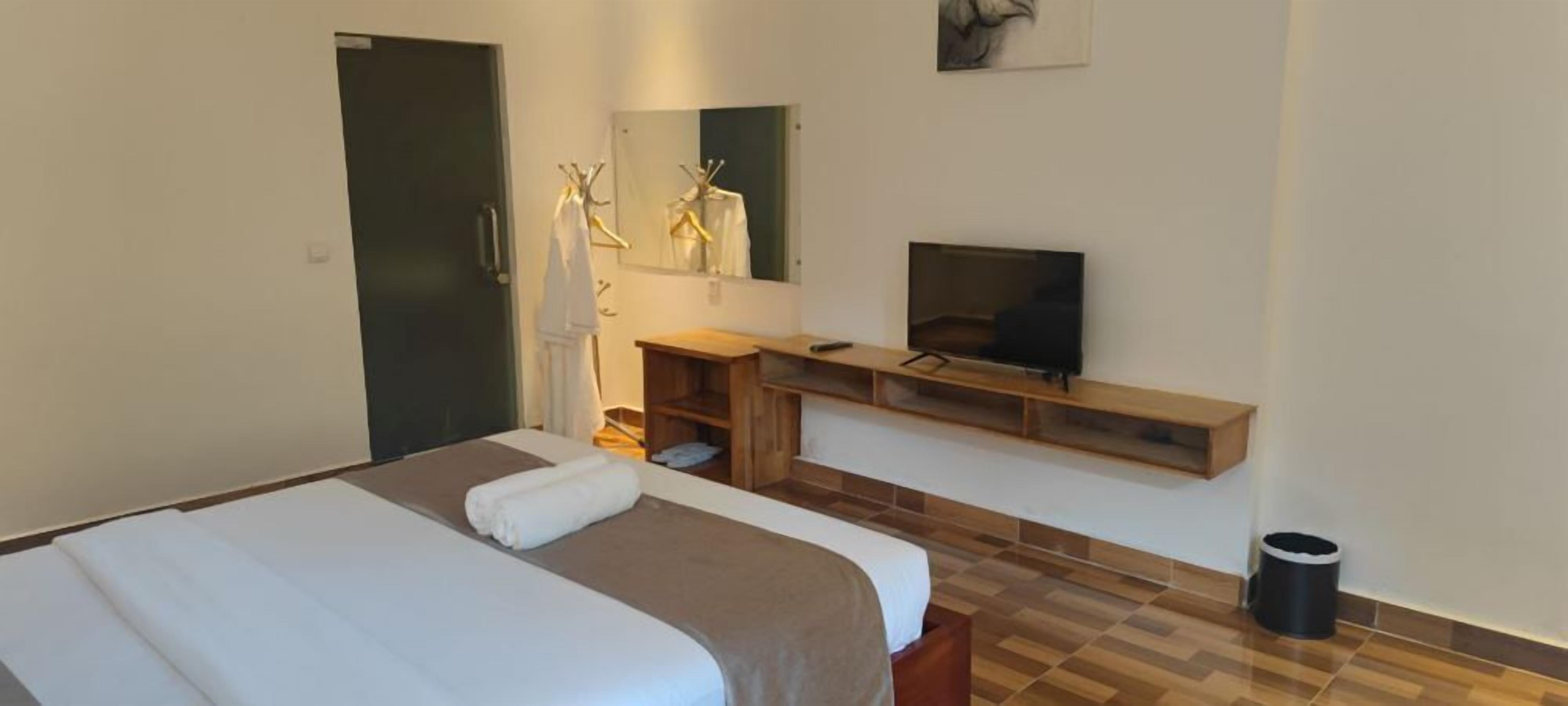 Ein Hotelzimmer mit Bett, Fernseher, Schreibtisch und Spiegel.