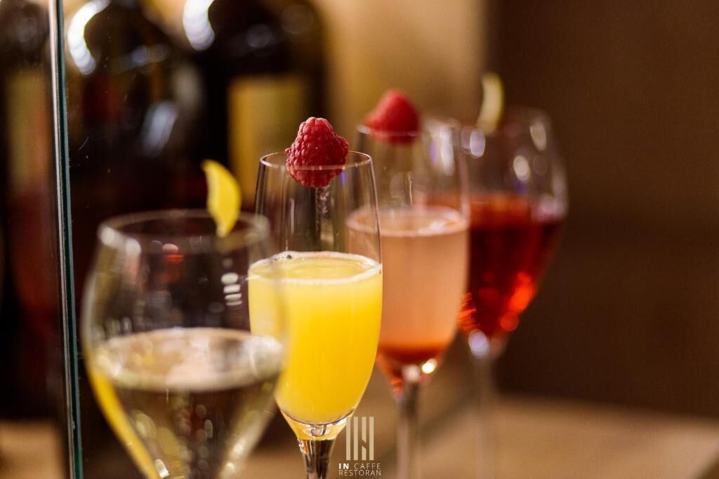 A bar setting with various glasses of beverages, some garnished with fruits.