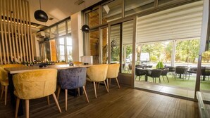 Uma sala de jantar moderna com piso de madeira, balcão bar e cadeiras amarelas.