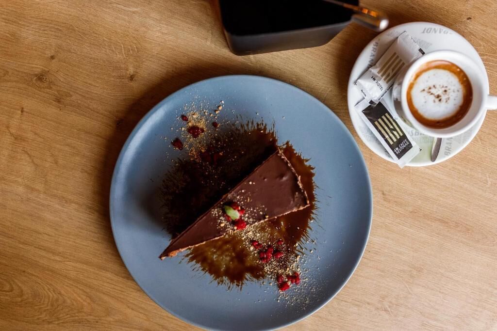 A dessert on a plate with a cup of coffee on a wooden table.