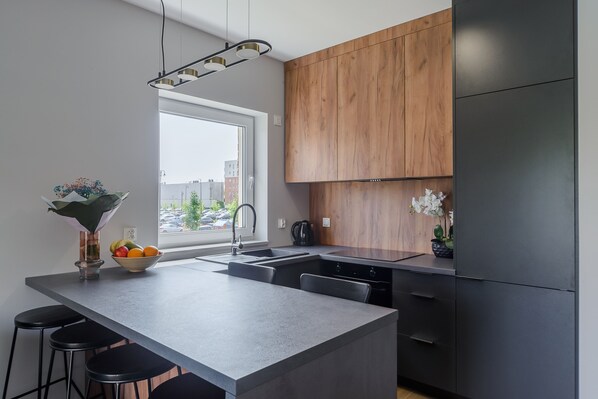 A modern kitchen with a large island, wooden cabinets, and a view of the city.