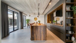 A modern kitchen with a wooden island, dark cabinetry, and a large window. - Villa Marli (Nin)