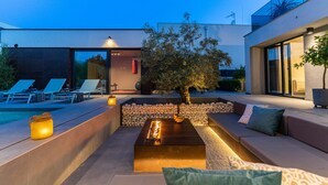 A modern outdoor living area with a fire feature, seating, and a tree. - Villa Marli (Nin)