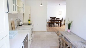Een moderne keuken met witte kasten, een spoelbak en een eethoek met houten stoelen en een tafel.
