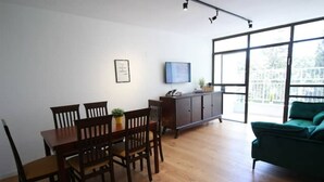 Een eetruimte met een houten tafel en stoelen, een kast en een televisie aan de muur.