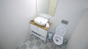Een badkamer met een witte wastafel, spiegel en toilet.