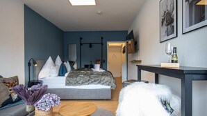 Een moderne, compacte woonruimte met een bed, een bank, een eethoek en een kleine keuken.