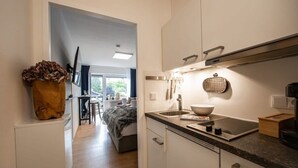 Een moderne keuken met witte kastjes, een zwart aanrecht en een groot raam.
