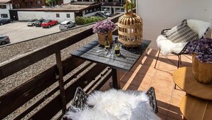 Een balkon met een tafel, stoelen en een decoratieve mand.