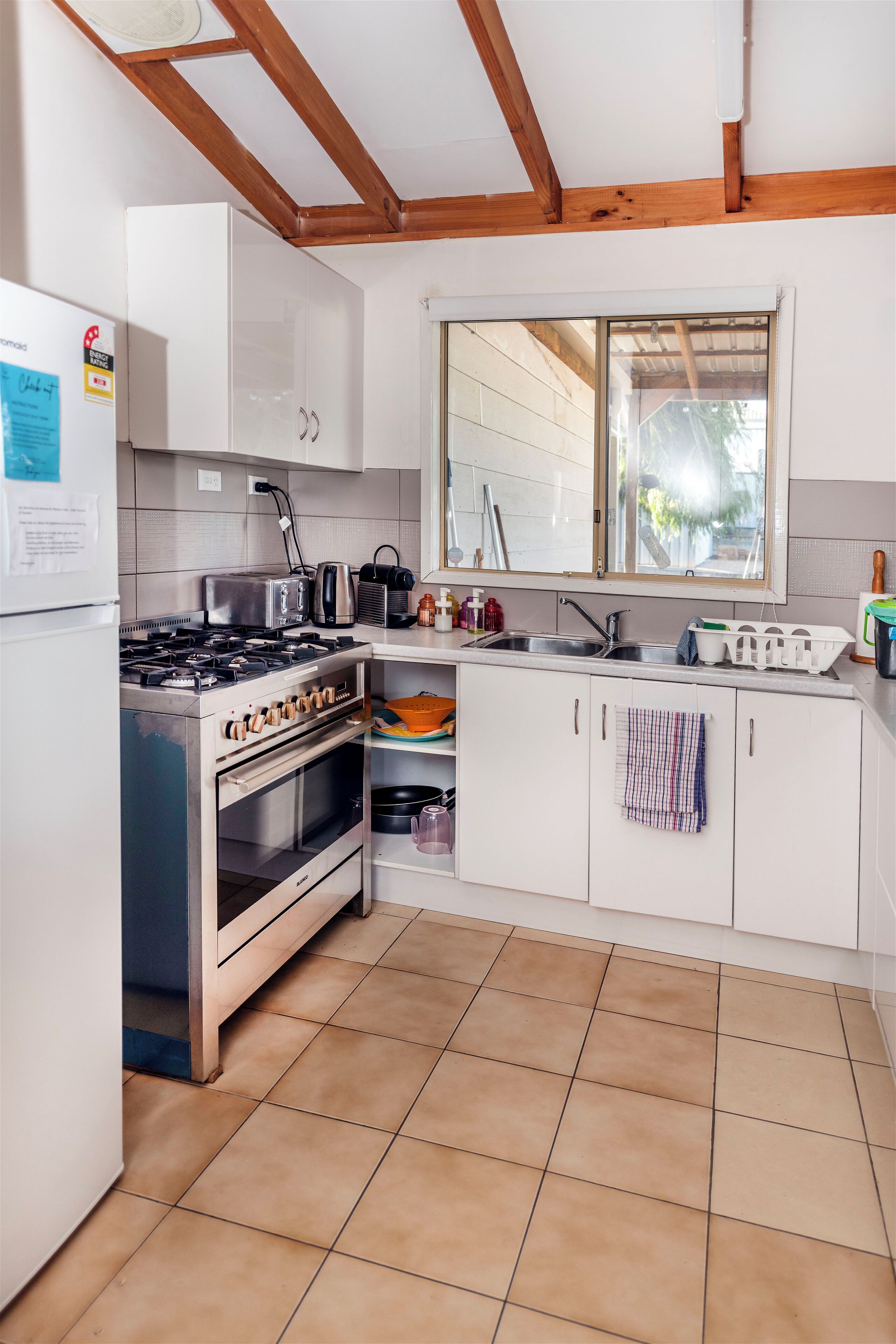 A kitchen with white cabinets, a stove, a sink, and a window above the sink.