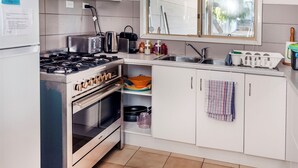 Una cucina con mobili bianchi, un fornello, un lavello e una finestra sopra il lavello.
