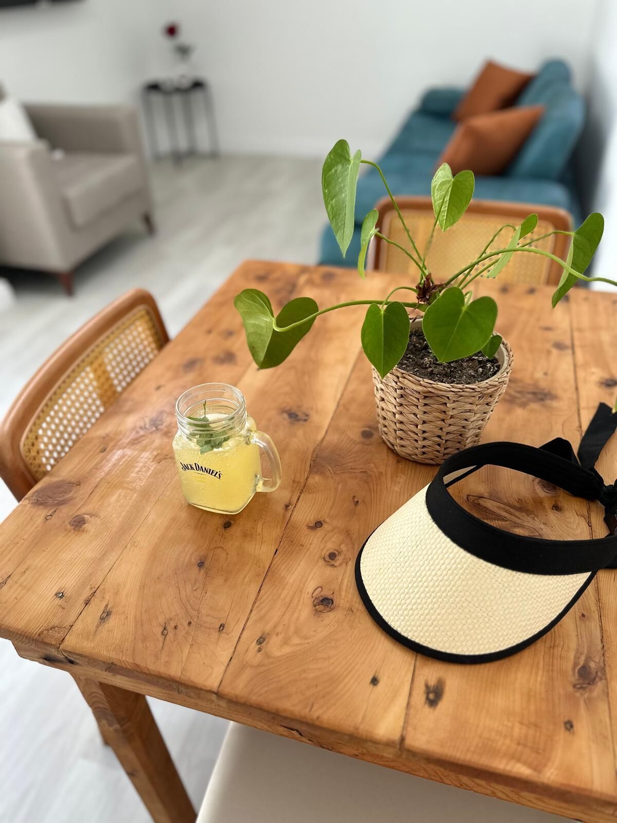 A wooden table with a potted plant, a glass jar, and a straw hat.