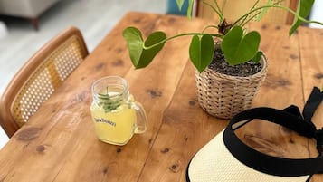 Un tavolo di legno con una pianta in vaso, un barattolo di vetro e un cappello di paglia.