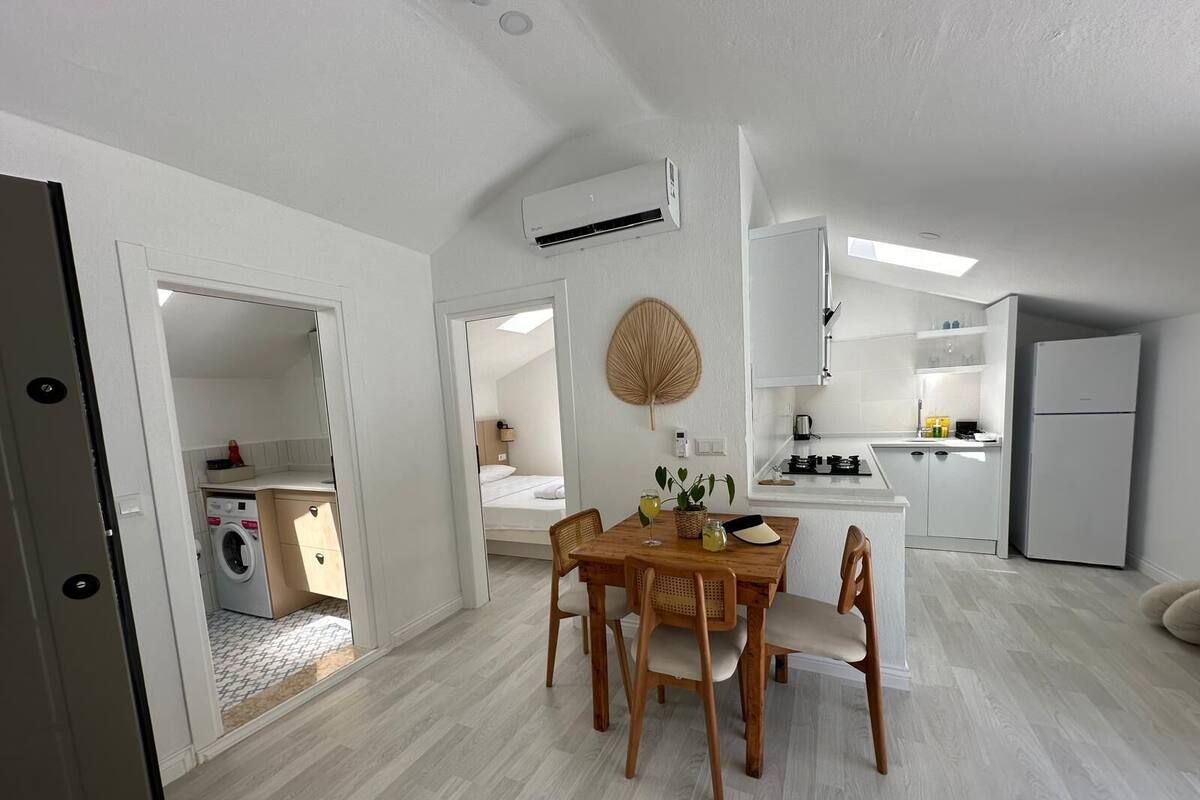 A modern apartment with a dining area, kitchen, and laundry room.