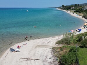 A beach with clear turquoise water, a sandy shore, and a few umbrellas.
