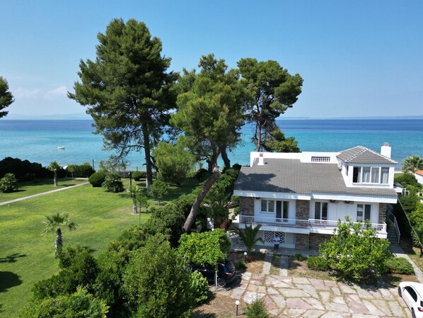 A coastal house with a stone facade, a balcony, and a view of the sea.