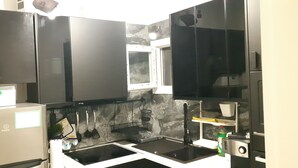 A modern kitchen with black cabinets, a built-in window, and a sink. - Luxury apartment near metro (Athina)