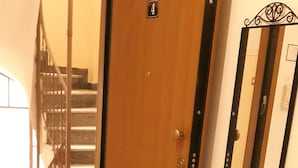 A wooden door with a number plate, a polished marble floor, and a mirror on the wall. - Luxury apartment near metro (Athina)