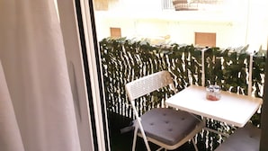 A small balcony with a white table and a single chair, a can of pasta, and a decorative plant barrier. - Luxury apartment near metro (Athina)