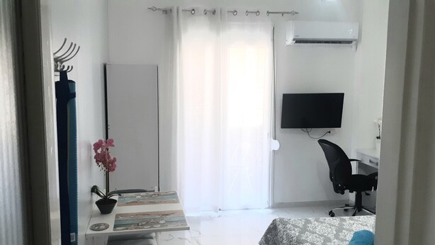 A bedroom with a bed, a desk, a chair, a TV, and a window with curtains. - Luxury apartment near metro (Athina)