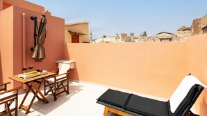 A rooftop terrace with a table, chairs, a lounge chair, and a view of the cityscape. - La Luna della Loggia A3 Suite, sensing the beat of the Old Town! (Rethymno)