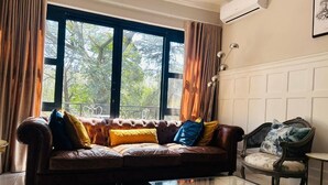 Un salon avec un canapé en cuir, une table basse en verre et un fauteuil à motifs.