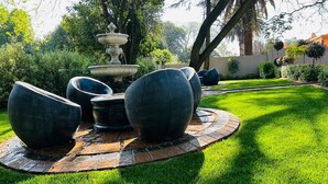 Un jardin agrémenté d’une fontaine, de grands jardinières et d’une pelouse parfaitement entretenue.