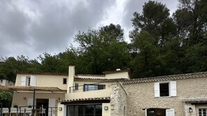 Un espace aménagé au bord de la piscine avec des chaises longues, un bâtiment en pierre doté d’un toit en tuiles et une piscine à l’eau d’un bleu cristallin.