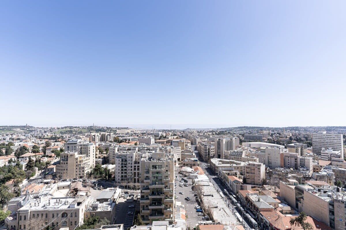 A cityscape with a mix of modern and traditional buildings, a clear sky, and a view of the distant horizon.
