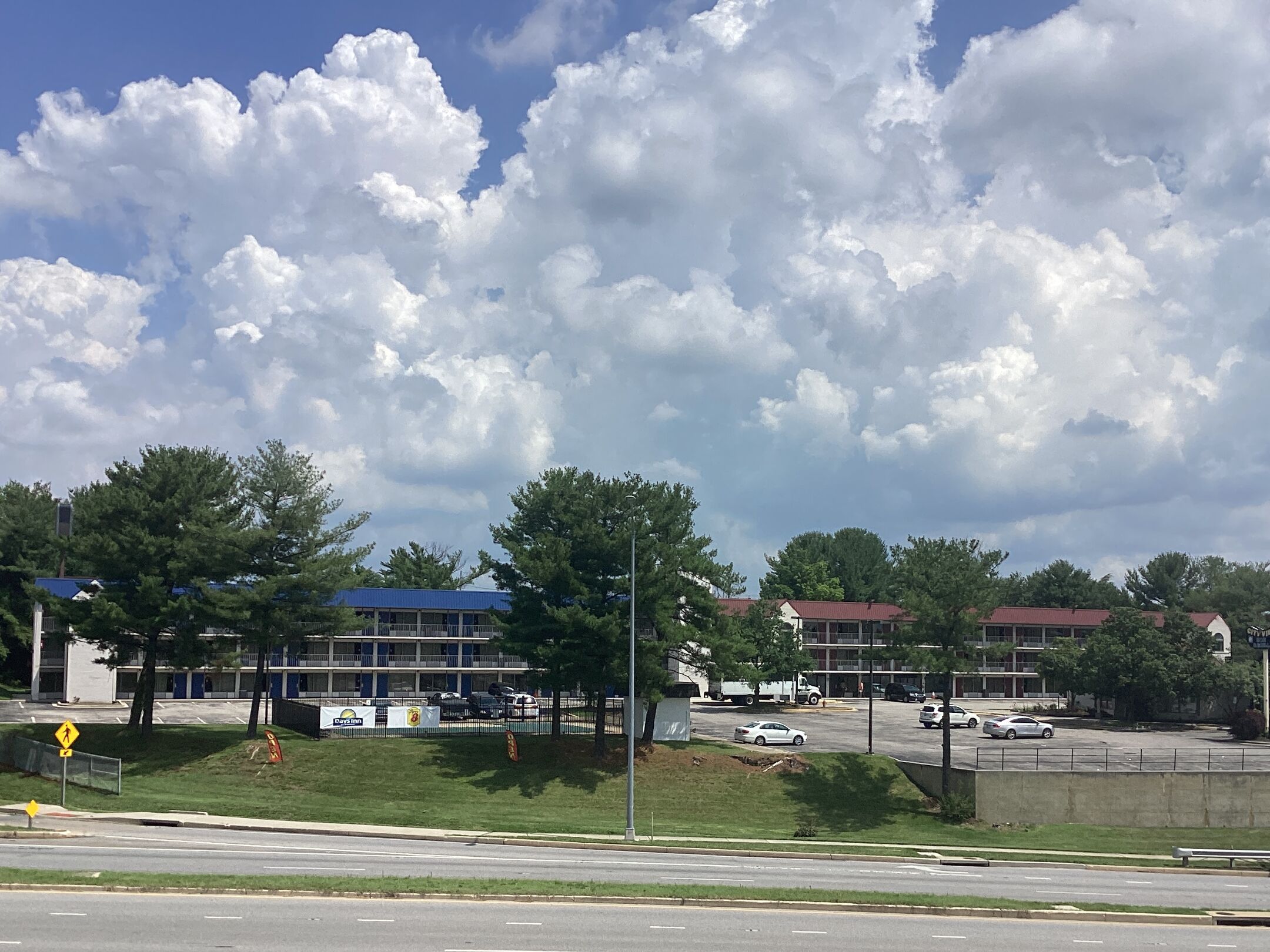 A commercial area with a parking lot, a building with a blue roof, and a pedestrian crossing sign.