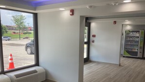 A clean, modern interior with a large window offering a view of a parking lot and a building outside. There is a vending machine and a fire alarm on the wall. - Super 8 By Wyndham Baltimore Northwest (Baltimore)