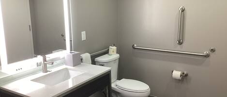 Ein modernes Badezimmer mit Waschtisch, Toilette und Handlauf.