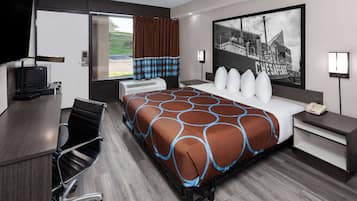 Habitación de hotel con una cama grande, un escritorio con silla, un televisor de pantalla plana, una ventana con cortinas y una lámpara de pared.