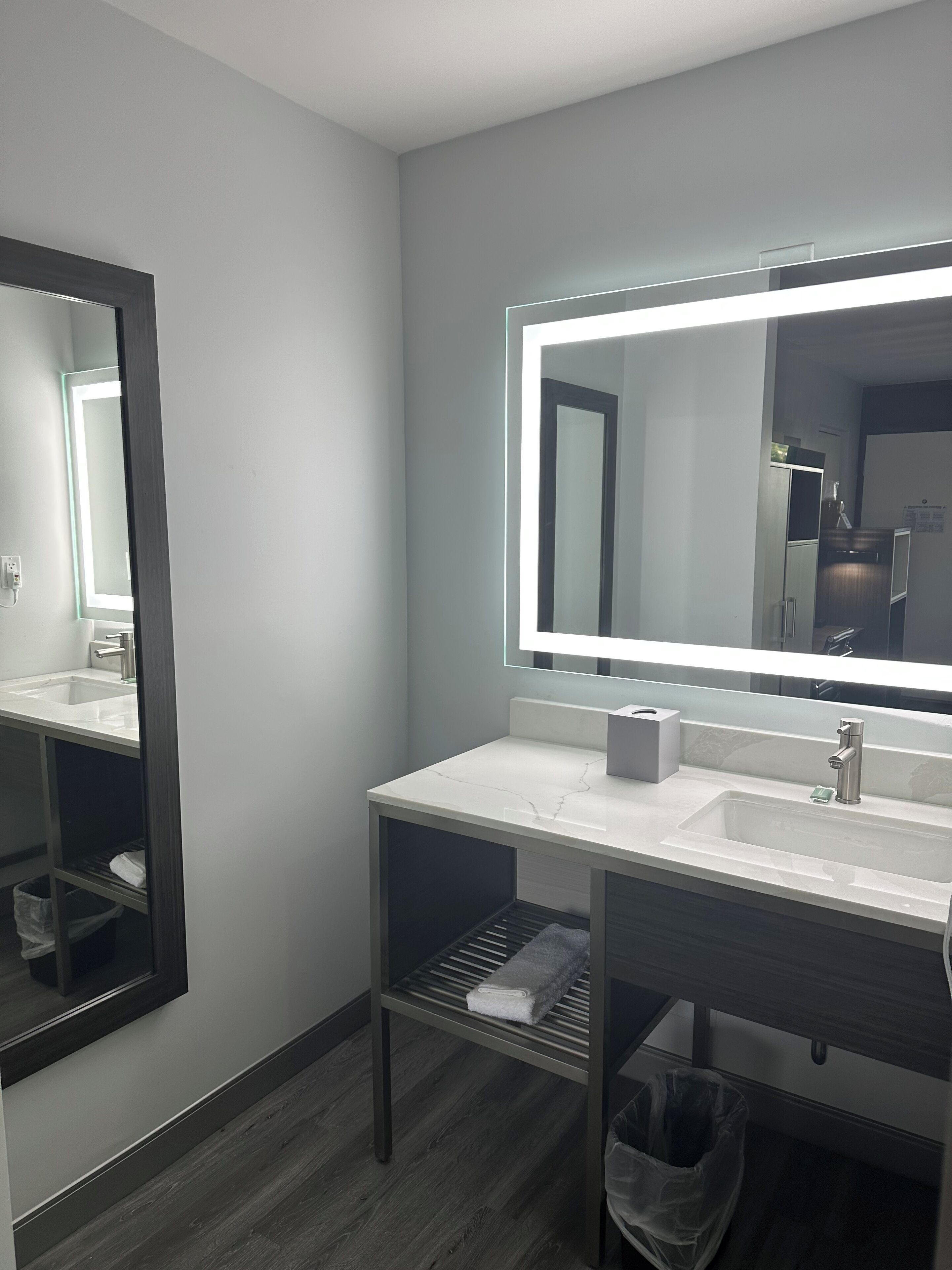 A modern bathroom with a large mirror, a sink, and a towel rack.