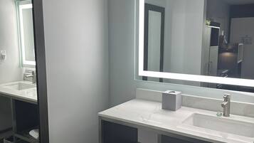 A modern bathroom with a large mirror, a sink, and a towel rack.