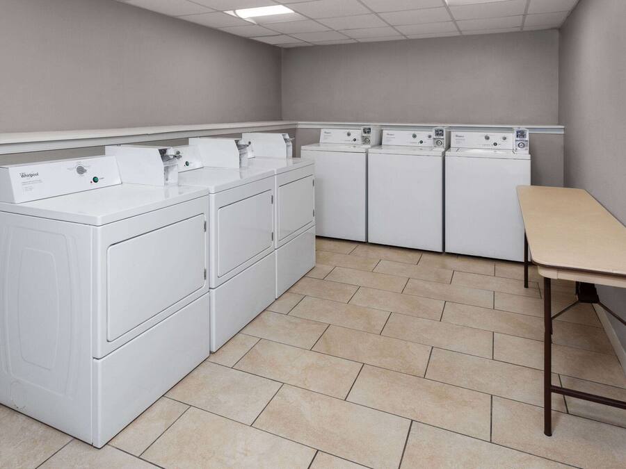 A laundry room with stacked washers and dryers, a table, and tiled flooring.