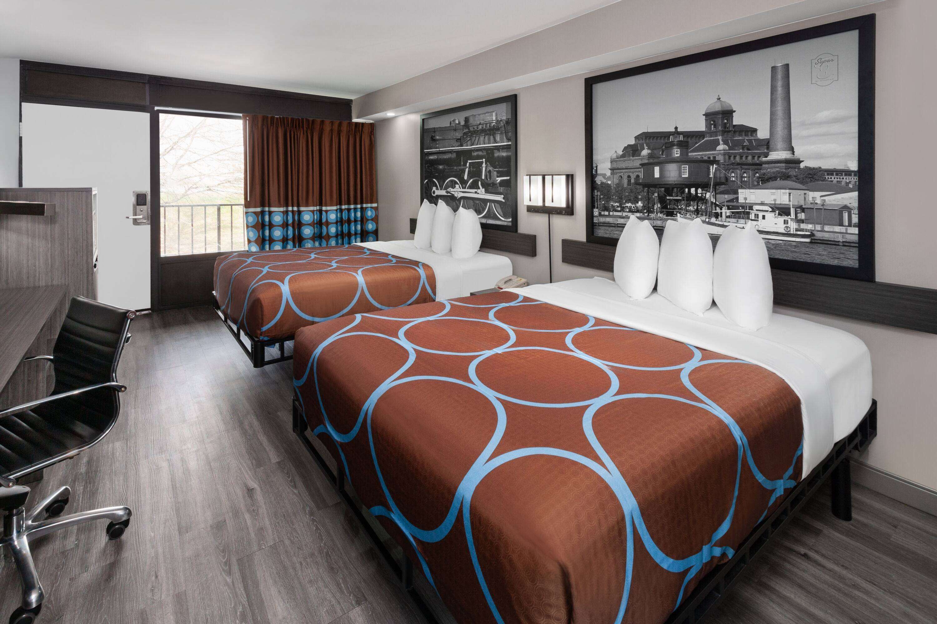 Habitación de hotel con dos camas, un escritorio y una silla.