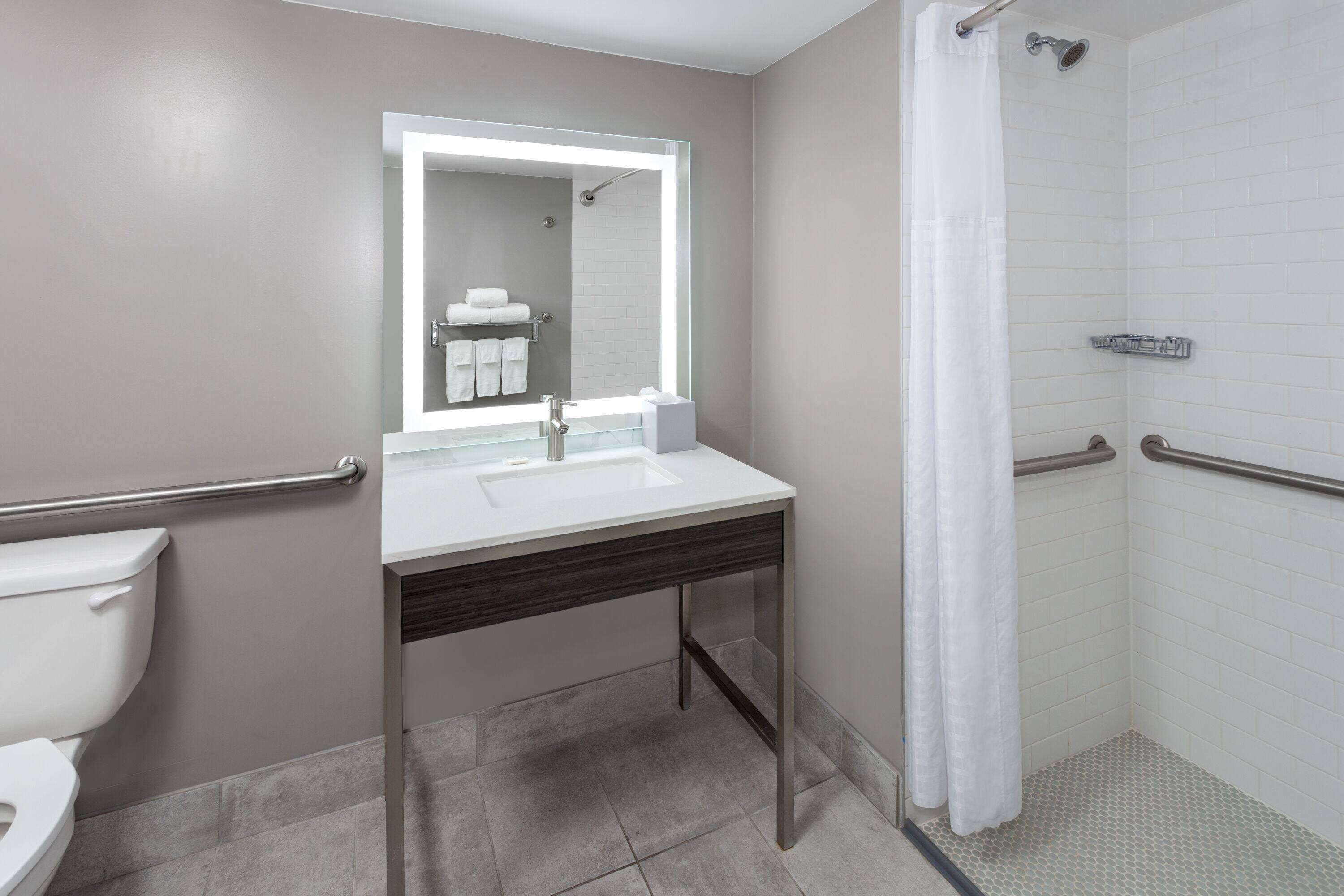 Une salle de bain moderne avec un lavabo blanc, un miroir et une douche.