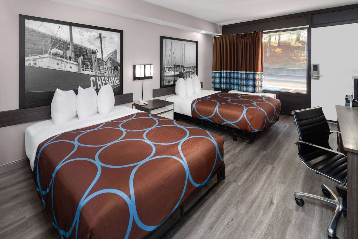 Hotellihuone, jossa on kaksi sänkyä, työpöytä ja tuoli.