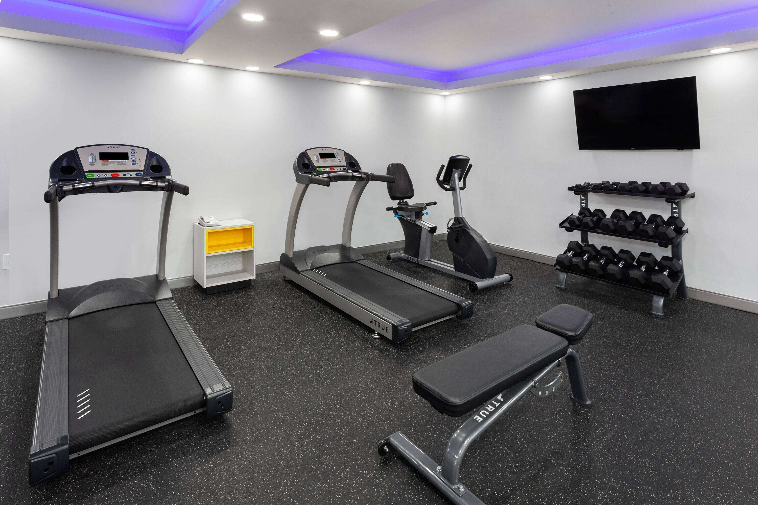 A gym with treadmills, an elliptical, and a bench.