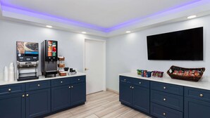 A modern kitchen with dark blue cabinets, a coffee machine, a flat-screen TV, and various food items on the counter. - Super 8 By Wyndham Baltimore Northwest (Baltimore)