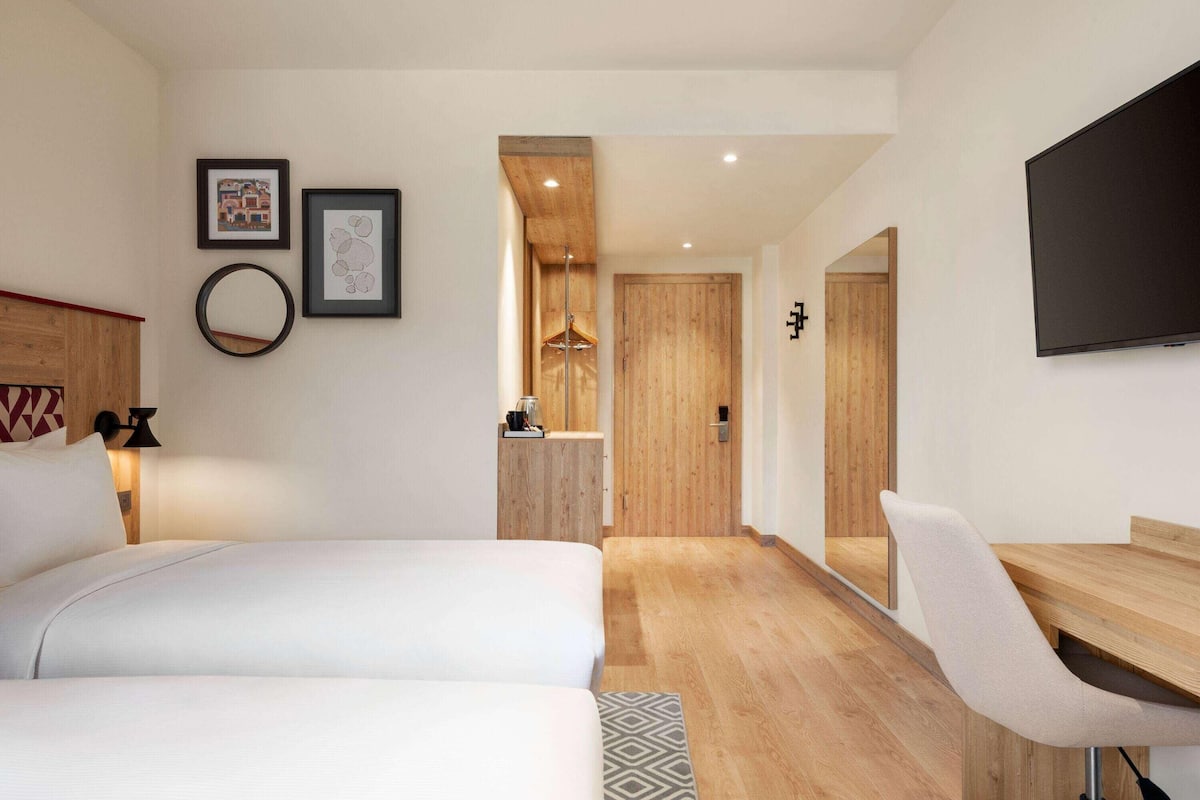 Une chambre d’hôtel moderne équipée d’un lit, d’un bureau et d’une télévision.